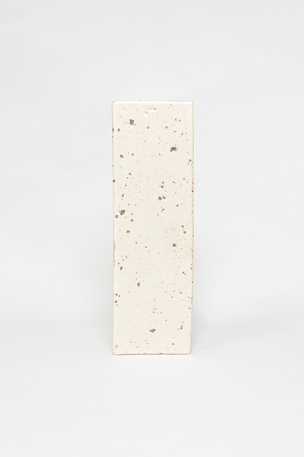 Artisan Antiquity cream thin brick tile with a matte glaze and scattered dark speckles