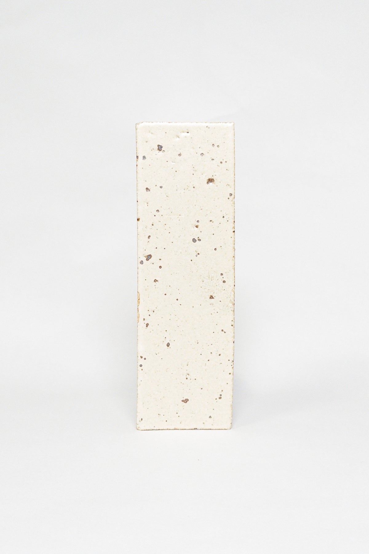 Artisan Antiquity cream thin brick tile with a matte glaze and scattered dark speckles