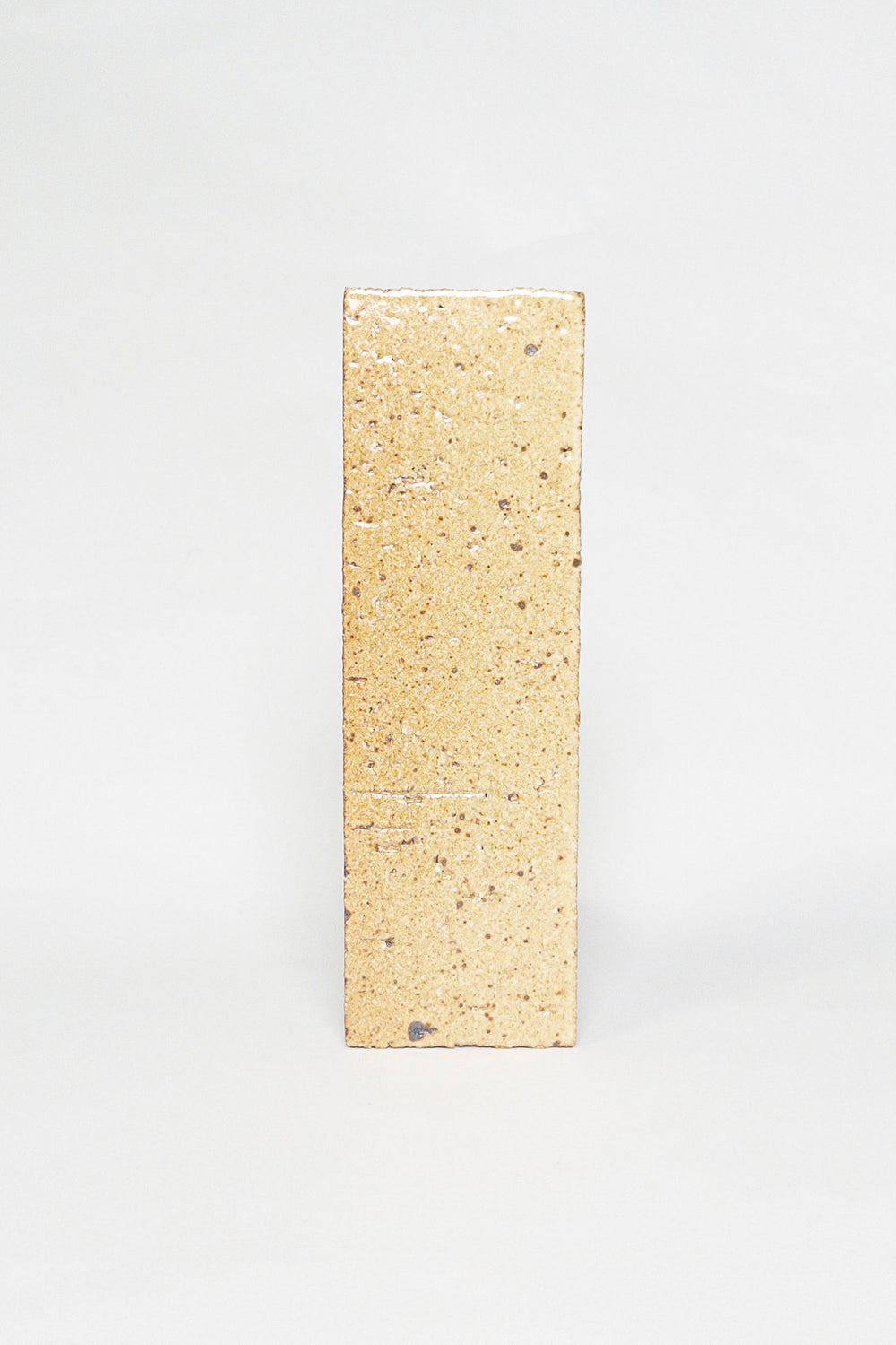 Artisan Biscotti golden beige thin brick tile with a glossy glaze and dark speckles
