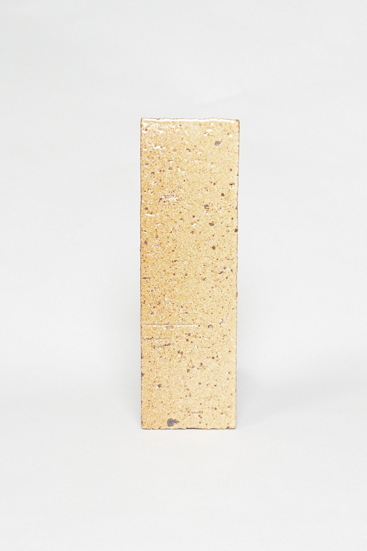 Artisan Biscotti golden beige thin brick tile with a glossy glaze and dark speckles